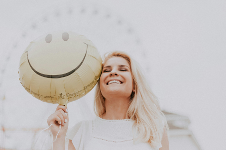 Noot. Door Julia Avamotive, 2018, foto, Pexels. https://www.pexels.com/photo/woman-holding-a-smiley-balloon-1236678/